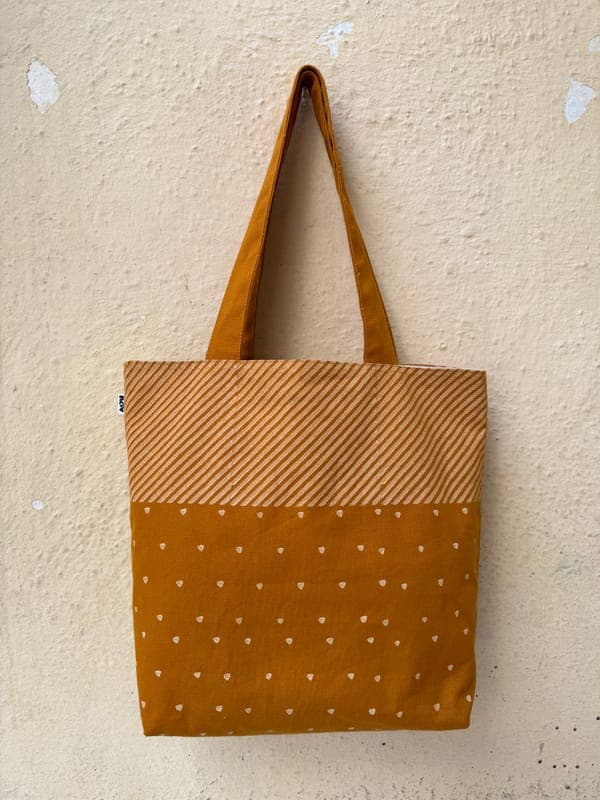 Mustard canvas tote with a diagonal stripe panel and scattered white hand-printed dots